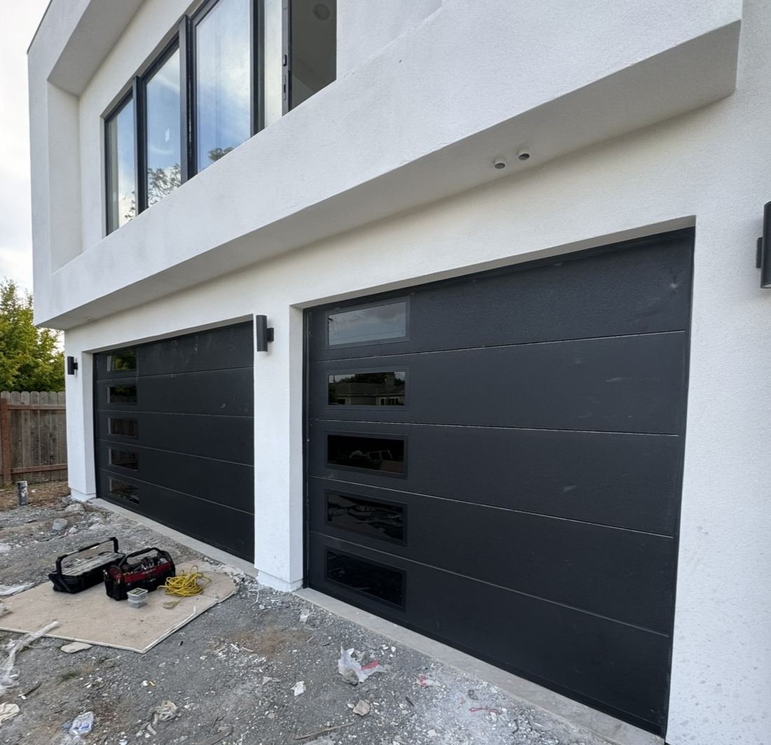 Two new black modern garage doors installed on a new-construction home