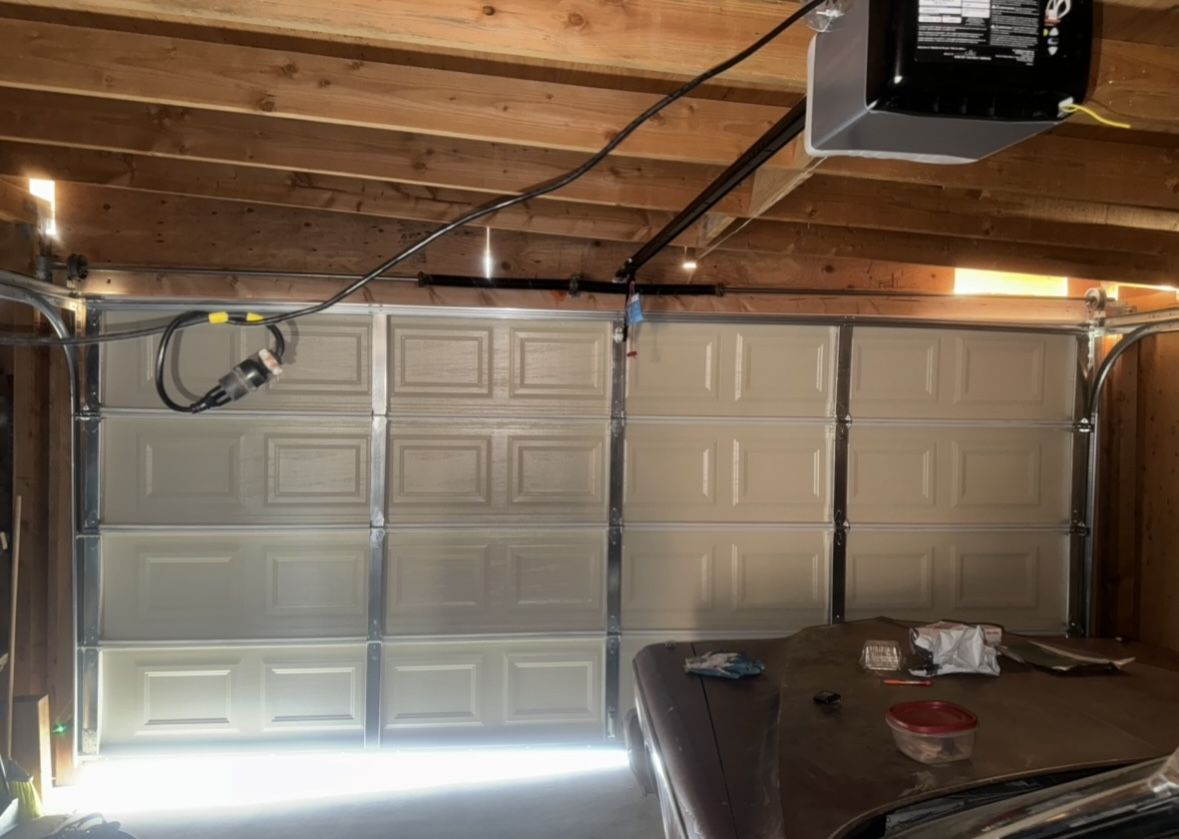New white sectional garage door and opener installed in a wood-beam garage